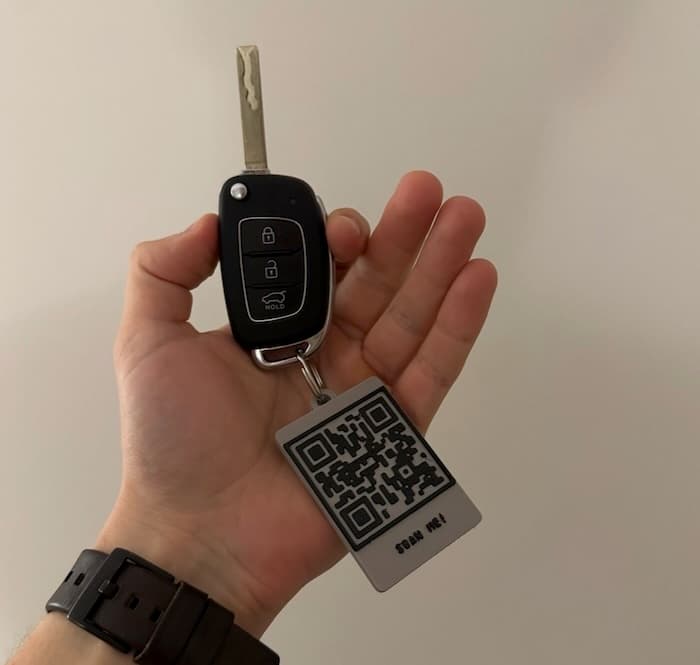 Hand holding a car key with a 3D printed RawTag QR code keychain attached